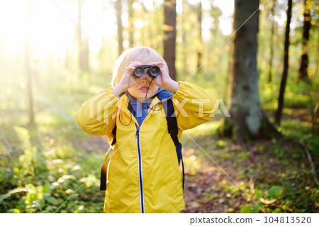 Little boy scout with binoculars during hiking in autumn forest. Child is looking with binoculars. 104813520