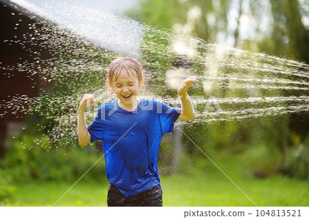 Funny little boy playing with garden sprinkler in sunny backyard. Preschooler child laughing, jumping and having fun with spray of water. Summer outdoors activity for kids. Funny little boy playing with garden sprinkler in sunny backyard. Preschooler child laughing, jumping and having fun with spray of water. Summer outdoors activity for kids. 104813521