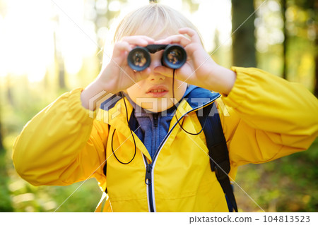 Little boy scout with binoculars during hiking in autumn forest. Child is looking with binoculars. 104813523