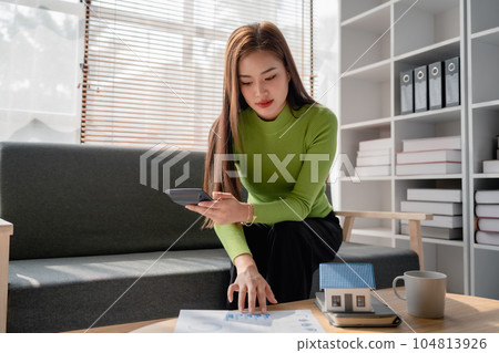 woman sitting on cozy sofa and planning and calculate expense and mortgage with calculator and home on desk, insurance and budget of residential, loan and residence, business and property concept woman sitting on cozy sofa and planning and calculate expense and mortgage with calculator and home on desk, insurance and budget of residential, loan and residence, business and property concept 104813926