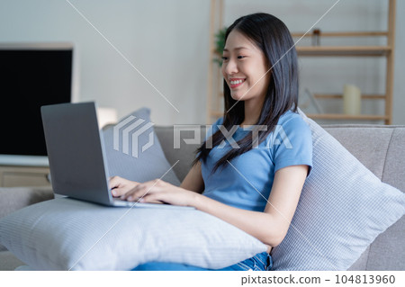 Asian Beautiful young woman relaxing on a couch at home with using computer laptop 104813960