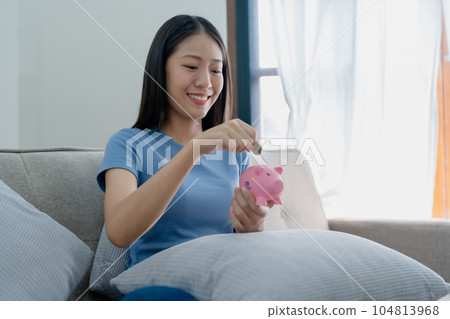 Asian young woman holding a piggy bank and coin, Savings concepts Asian young woman holding a piggy bank and coin, Savings concepts 104813968