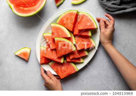 Female hands holding a plate with fresh juicy watermelon slices. Female hands holding a plate with fresh juicy watermelon slices. 104813969