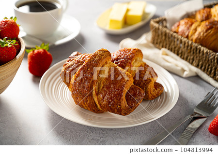 Fresh sweet croissants for breakfast, with butter, coffee and fresh strawberries. 104813994