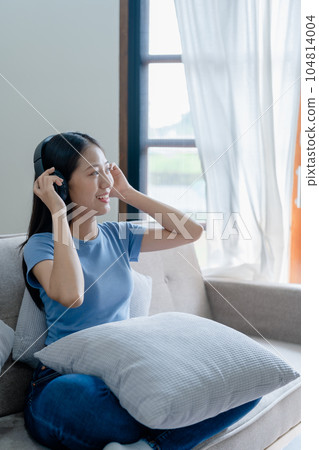 Peaceful girl in modern wireless headphones sit relax on comfortable couch listening to music, on cozy sofa, stress free concept Peaceful girl in modern wireless headphones sit relax on comfortable couch listening to music, on cozy sofa, stress free concept 104814004