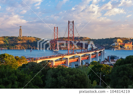 View of Lisbon view from Miradouro do Bairro do Alvito tourist viewpoint of Tagus river, traffic on 25th of April Bridge, and Christ the King statue at sunset. Lisbon, Portugal View of Lisbon view from Miradouro do Bairro do Alvito tourist viewpoint of Tagus river, traffic on 25th of April Bridge, and Christ the King statue at sunset. Lisbon, Portugal 104814219