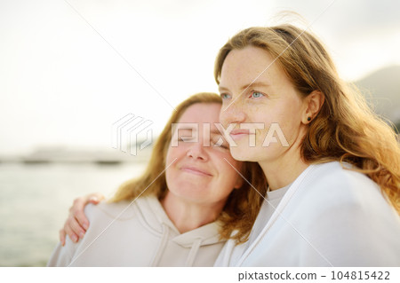 Redhead senior mother and her beautiful adult daughter are walking together and laughing 104815422