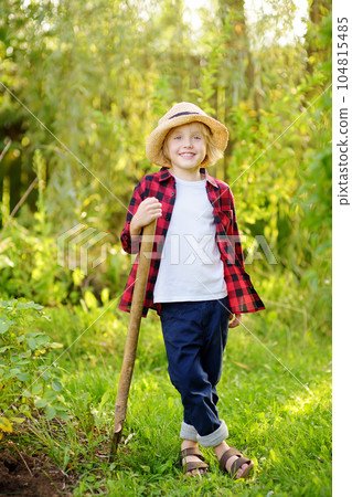 Little schoolboy holding with shovel on the domestic garden at summer sunny day. Family gardening activity with kids 104815485