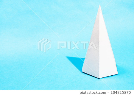 tall hand-crafted paper pyramid on turquoise blue 104815870