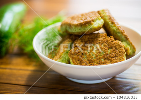 fried zucchini pancakes with herbs, in a plate . 104816015