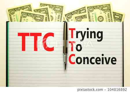TTC trying to conceive symbol. Concept words TTC trying to conceive on white note on a beautiful background from dollar bills. Pen. Medical and TTC trying to conceive concept. Copy space. 104816892