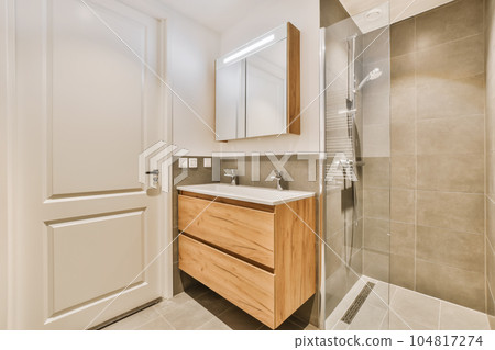 a modern bathroom with wood cabinets and white fixtures on the countertop, shower stall and toilet in the background 104817274