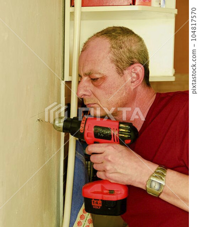 Mid-adult man drilling hole in the wall. Closeup concept. 104817570