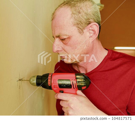Mid-adult man drilling hole in wall. Closeup concept 104817571