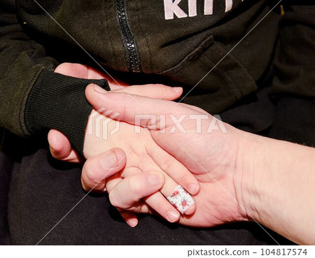Hand man holding hand girl child. Girl child with sticking plaster on finger. Concept idea. Family and father concept. Hand man holding hand girl child. Girl child with sticking plaster on finger. Concept idea. Family and father concept. 104817574