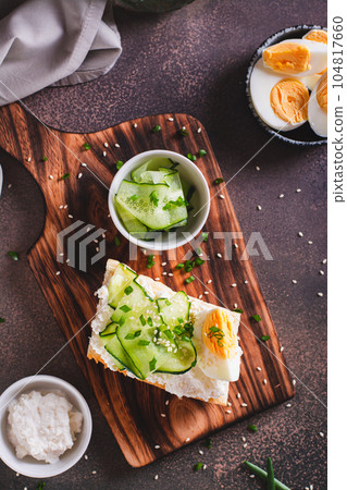 Bruschetta with ricotta, cucumber, boiled egg and sesame seeds on a board top and vertical view 104817660