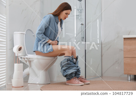 Woman suffering from hemorrhoid on toilet bowl in rest room Woman suffering from hemorrhoid on toilet bowl in rest room 104817729