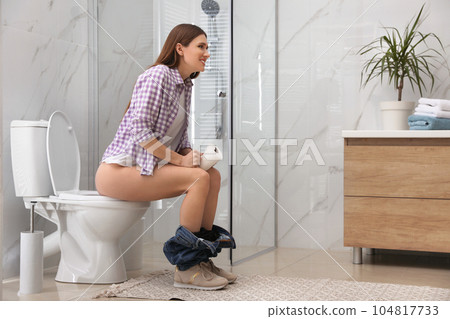 Woman with paper suffering from hemorrhoid on toilet bowl in rest room Woman with paper suffering from hemorrhoid on toilet bowl in rest room 104817733
