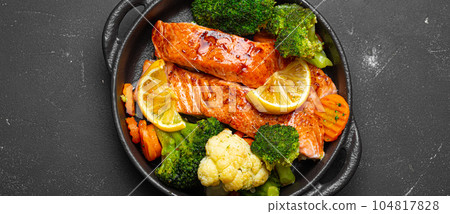 Healthy baked fish salmon steaks, broccoli, cauliflower, carrot in cast iron casserole bowl on black dark stone background. Cooking a delicious low carb dinner, healthy nutrition Healthy baked fish salmon steaks, broccoli, cauliflower, carrot in cast iron casserole bowl on black dark stone background. Cooking a delicious low carb dinner, healthy nutrition 104817828