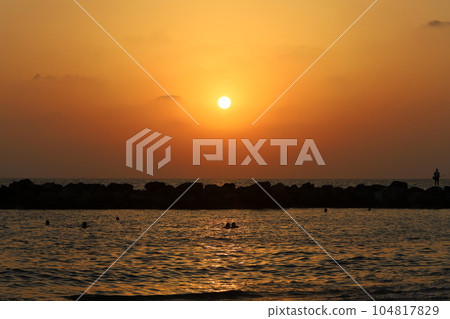 The sun sets over the horizon on the shores of the Mediterranean Sea 104817829
