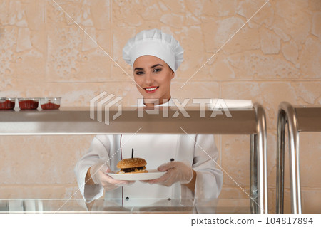 School canteen worker with burger at serving line. Tasty food 104817894