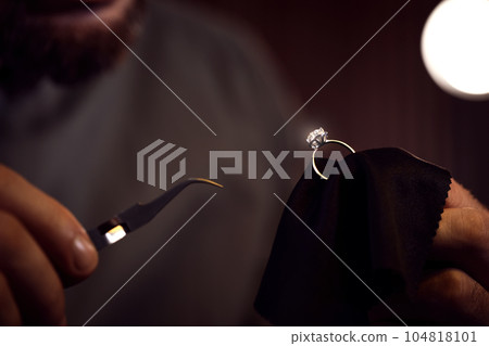 Jeweler working with ring on blurred background, closeup Jeweler working with ring on blurred background, closeup 104818101