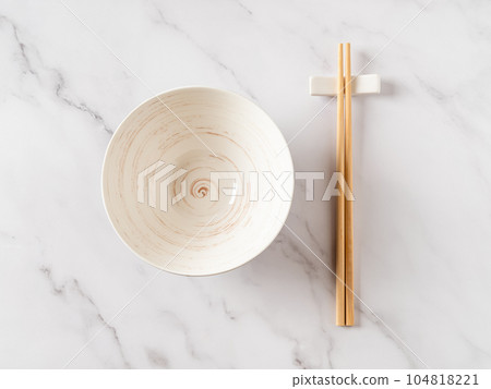 Empty white bowl and bamboo chopsticks over marble table. Empty white bowl and bamboo chopsticks over marble table. 104818221
