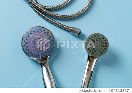 Old and new handheld shower heads over blue background.  104818227