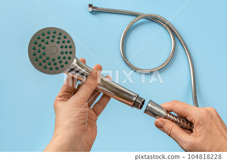 Woman hands connecting the hose to a shower head. 104818228