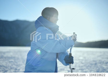 一名二十多歲的婦女在冰凍的湖面上鑽洞 104818622