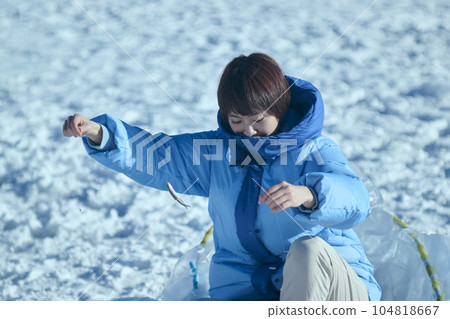 一名二十多歲的婦女在冬季湖中捕魚胡瓜魚 一名二十多歲的婦女在冬季湖中捕魚胡瓜魚 104818667