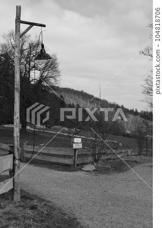 Grayscale of an old lantern with wooden pole in front of Steinberg Alm in Harz Mountains, Germany Grayscale of an old lantern with wooden pole in front of Steinberg Alm in Harz Mountains, Germany 104818706