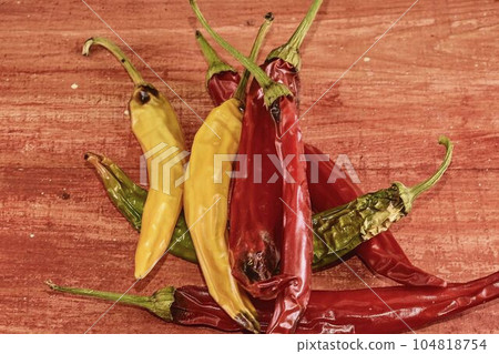 Shrinking and mould chili peppers on red wooden background. Rotten chili peppers 104818754