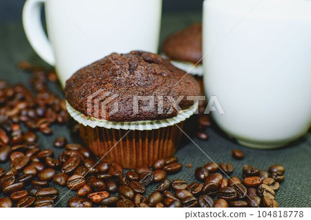 Dark muffins, cups of coffee and coffee beans on black background. 104818778
