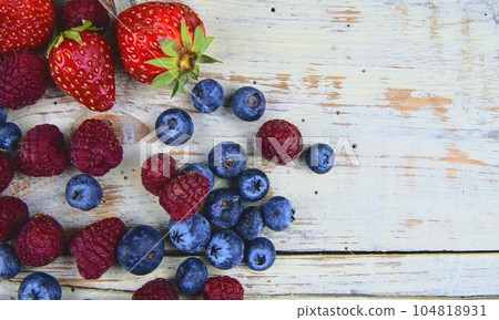 Healthy mixed fruit and ingredients with strawberry, raspberry, blueberry from top view. Berries on rustic white wooden background. Flat design. Free space for text. Copy space for banner 104818931