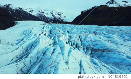 Aerial view of massive glacier caps in nordic scenery, beautiful large vatnajokull ice blocks in iceland. Blue icebergs and icy rocks near frozen lake and snowy mountains. Slow motion. Aerial view of massive glacier caps in nordic scenery, beautiful large vatnajokull ice blocks in iceland. Blue icebergs and icy rocks near frozen lake and snowy mountains. Slow motion. 104819261