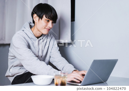Smiling Japanese man in his thirties chatting online on his laptop at home late at night Smiling Japanese man in his thirties chatting online on his laptop at home late at night 104822470