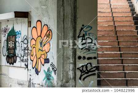 The old cement staircase and the graffiti patterns on cement wall is in the abandoned building and was left to deteriorate over years. 104822996