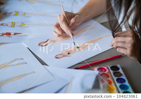 Faceless woman draws sketches of swimwear. Close-up of the hands of a fashion designer. 104823061