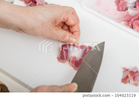 [Housewife preparing yakitori gizzards with a knife] 104823119