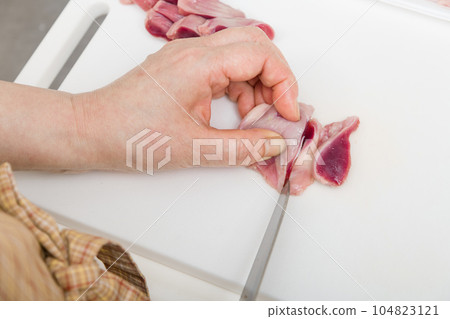 [Housewife preparing yakitori gizzards with a knife] 104823121