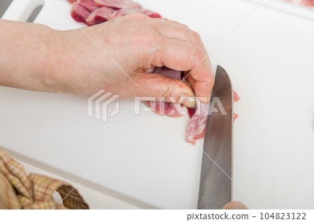 [Housewife preparing yakitori gizzards with a knife] 104823122