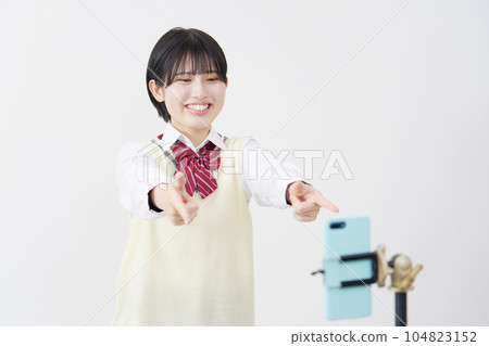 A high school girl taking a selfie video with her smartphone White background 104823152