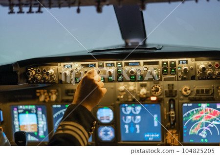 A man is studying to be a pilot in a flight simulator. Close-up of male hands on the control panel of an aircraft. A man is studying to be a pilot in a flight simulator. Close-up of male hands on the control panel of an aircraft. 104825205