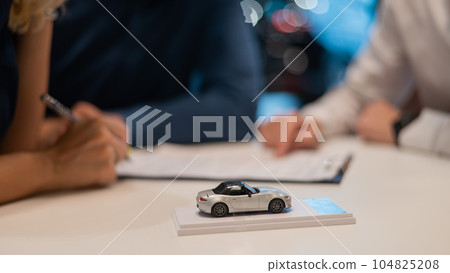 Close-up of the couple's hands signing a contract to buy a car salon. Close-up of the couple's hands signing a contract to buy a car salon. 104825208