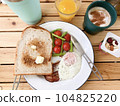 Cappuccino with cinnamon on a white plate with toast, bacon eggs and tomatoes on a wooden table 104825220