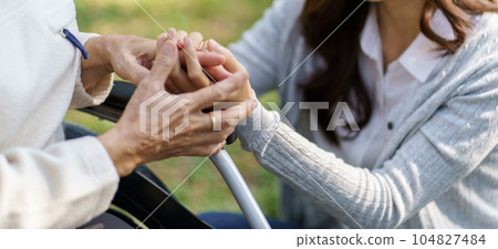 Asian senior woman in wheelchair with happy daughter. Family relationship retired woman sitting on wheelchair in the park age care at retirement home. 104827484