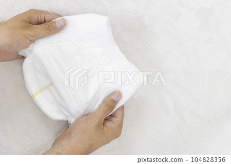 Man's hand holding paper diaper 104828356
