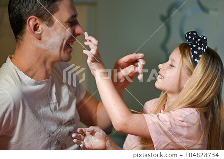 Father and daughter soil each other with flour Father and daughter soil each other with flour 104828734