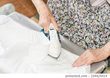 Senior woman ironing a white cutter shirt Senior woman ironing a white cutter shirt 104828814